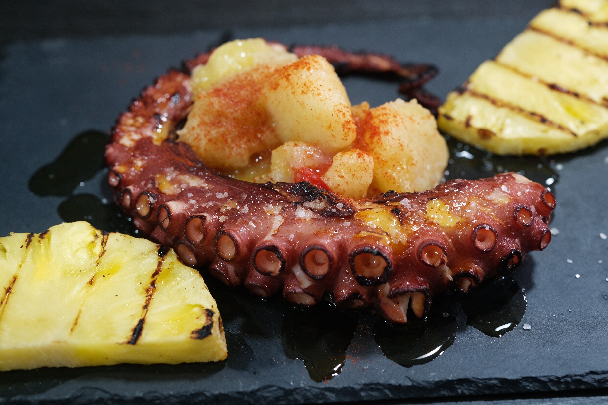 Pata de pulpo a la parrilla con pimentón sobre patata y piña a la plancha
