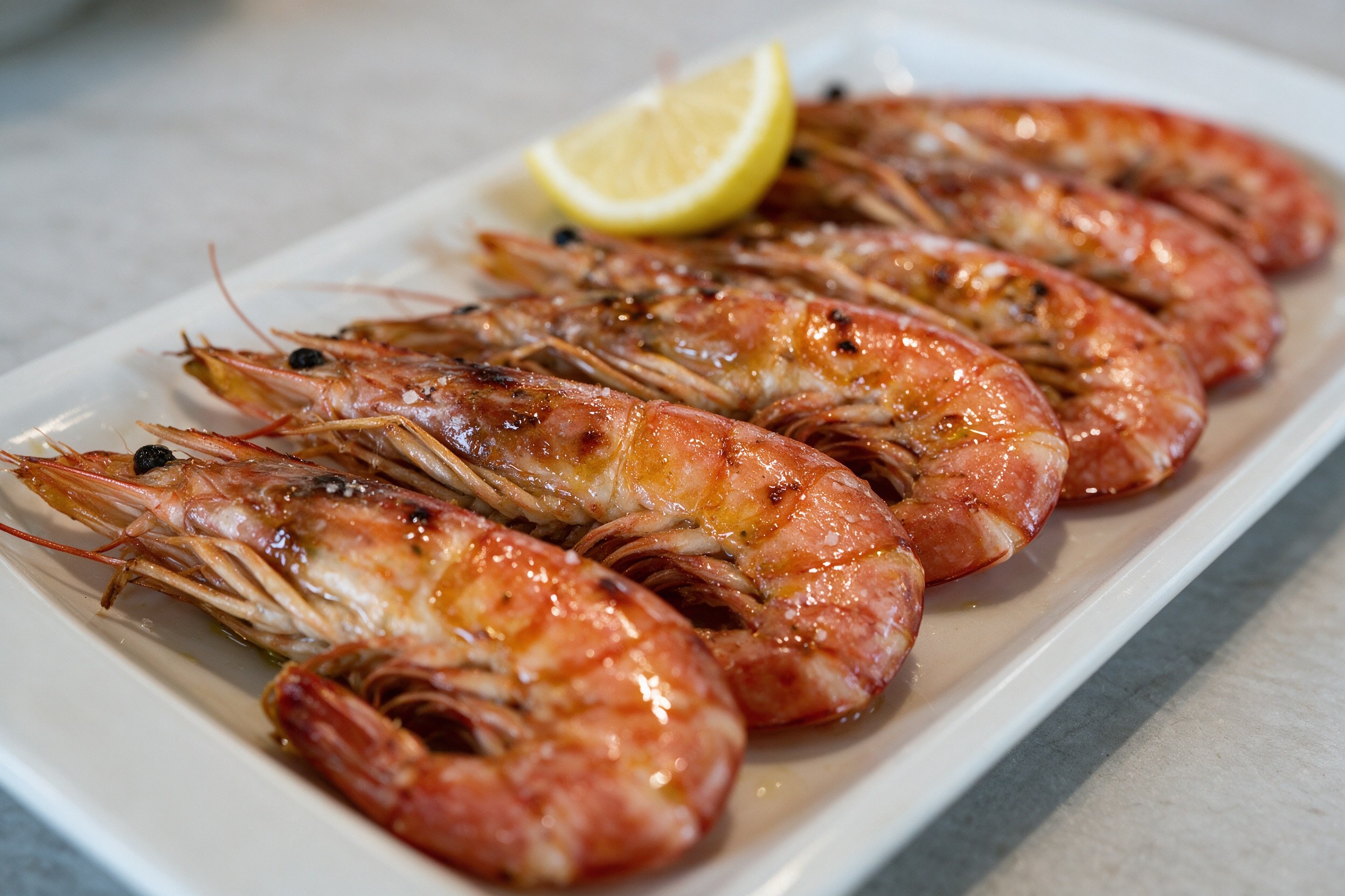 Langostinos rojos a la plancha en bandeja blanca con limón